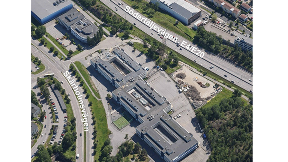 Flygfoto över ett område i Sätra mellan E4 Södertäljevägen  och Skärholmsvägen.  Skolbyggnaden i mitten av fotot.